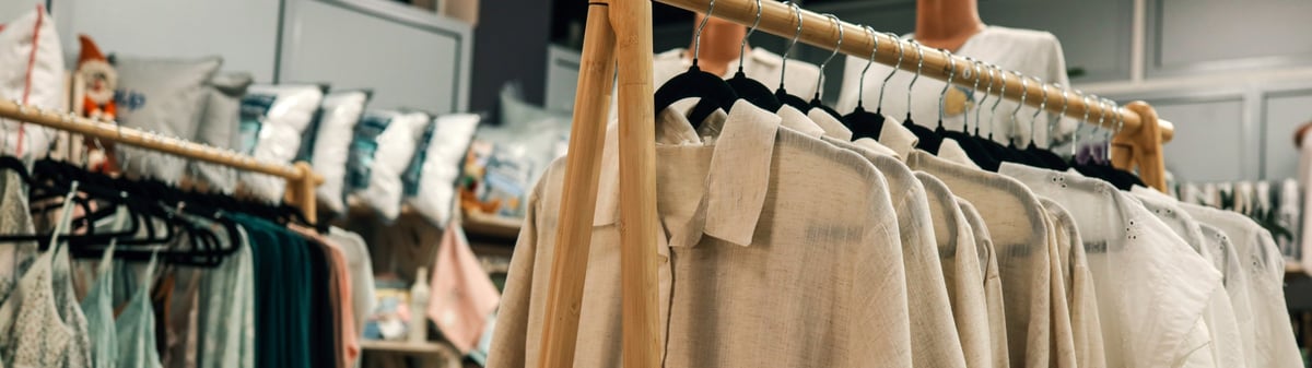 Neutral-toned clothing hanging on a bright boutique rack