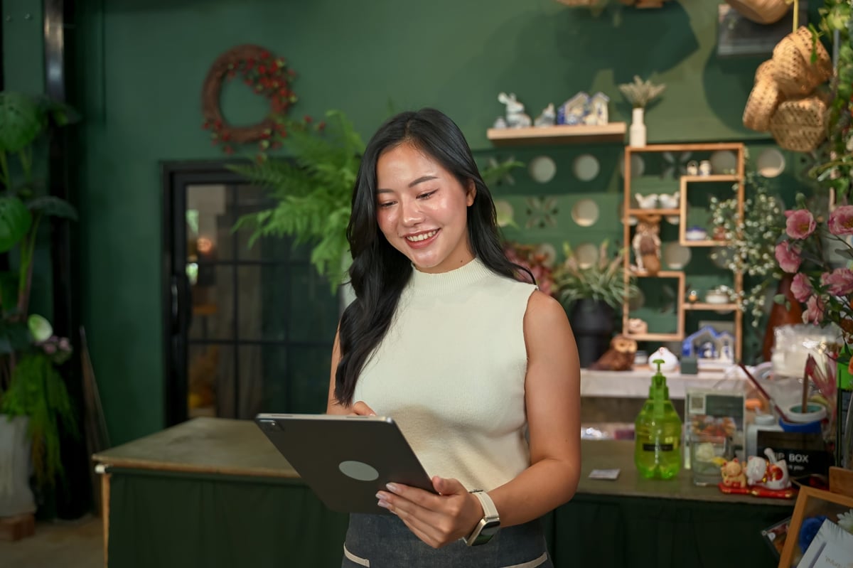 Shop owner reviewing orders on a tablet inside a bright store
